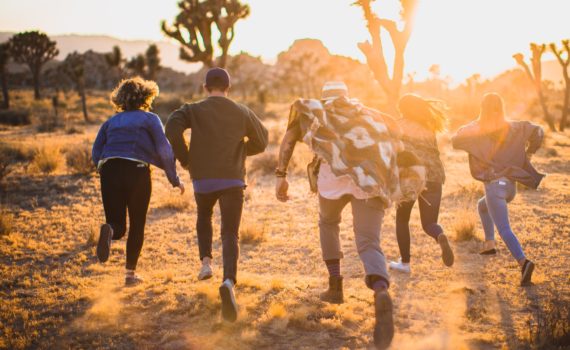 fiver person running on the field near trees